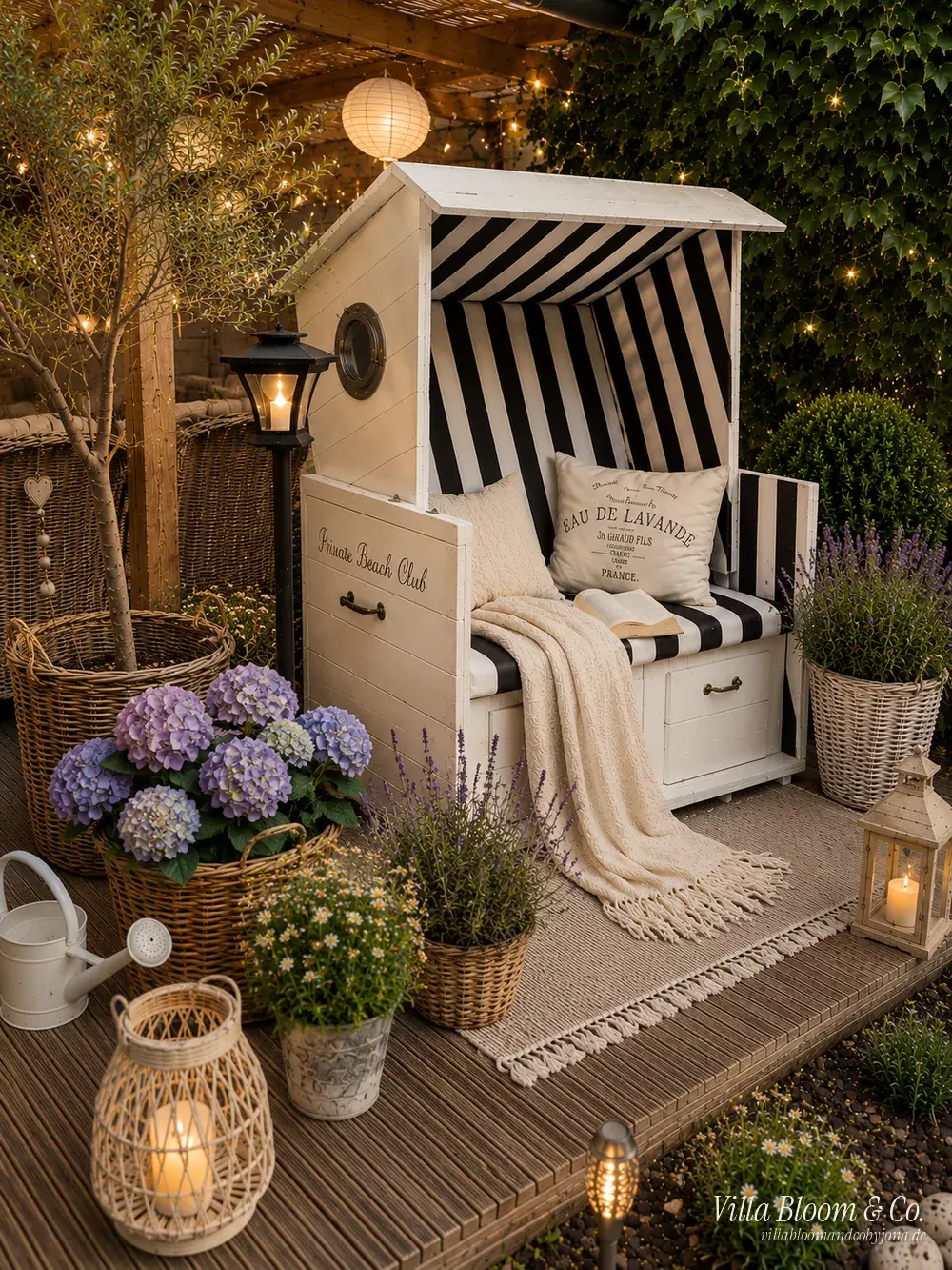 Gemütliche Sommerterrasse im Landhausstil mit Strandkorb, Hortensien, Lavendel und Lichterketten am Abend