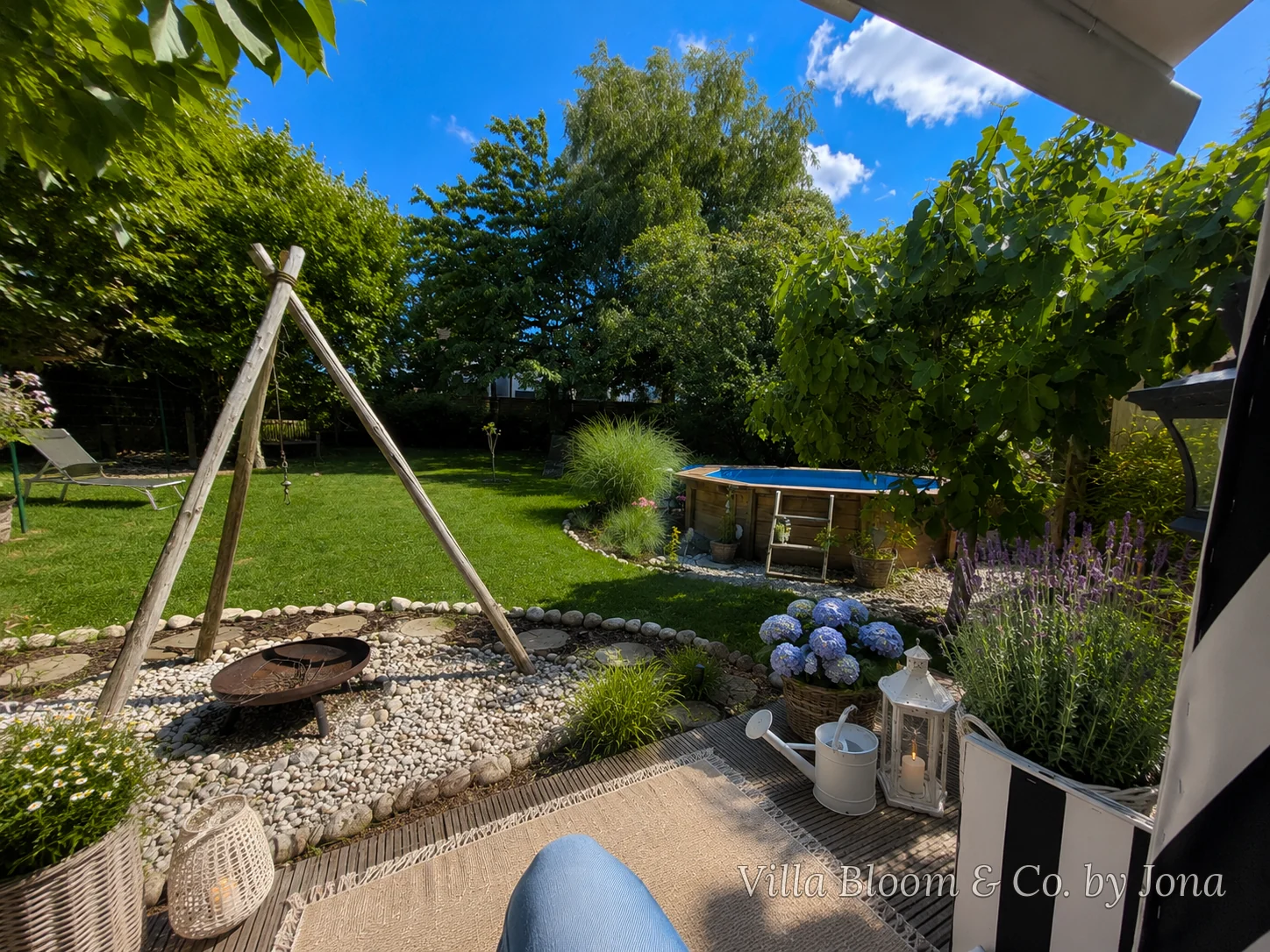 Blick aus meinem Strandkorb über den Sommergarten mit Pool, Feuerstelle, Lavendel und Hortensien unter blauem Himmel