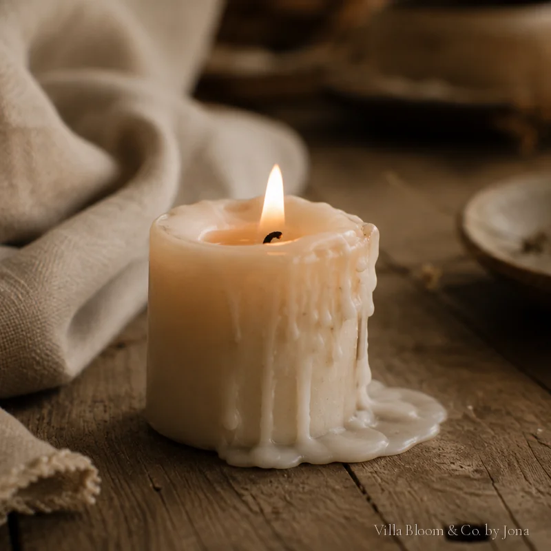 A candle burned low on rustic wood with linen