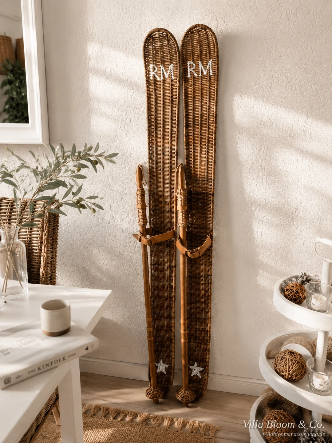Paar Ski aus Rattan mit RM-Schriftzug an der Wand, daneben winterliche Deko