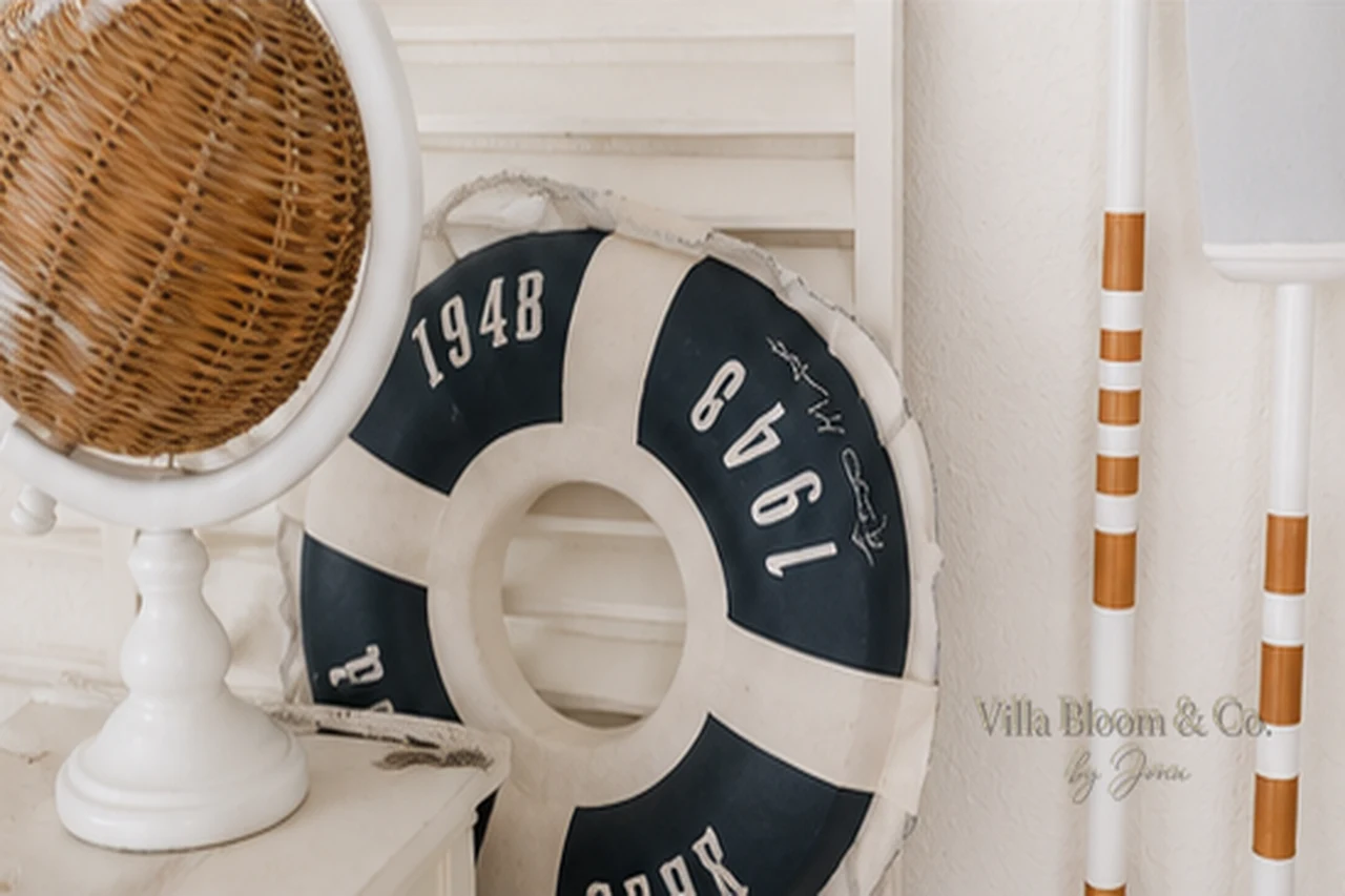 Maritimer Rettungsring und Rattan-Globus neben weißem Sideboard